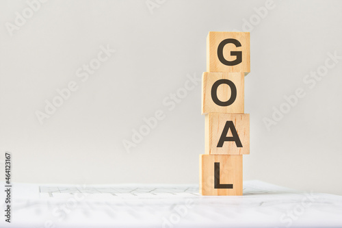 word GOAL with wood building blocks, light gray background. document with numbers on background, business concept. space for text in left. front view.