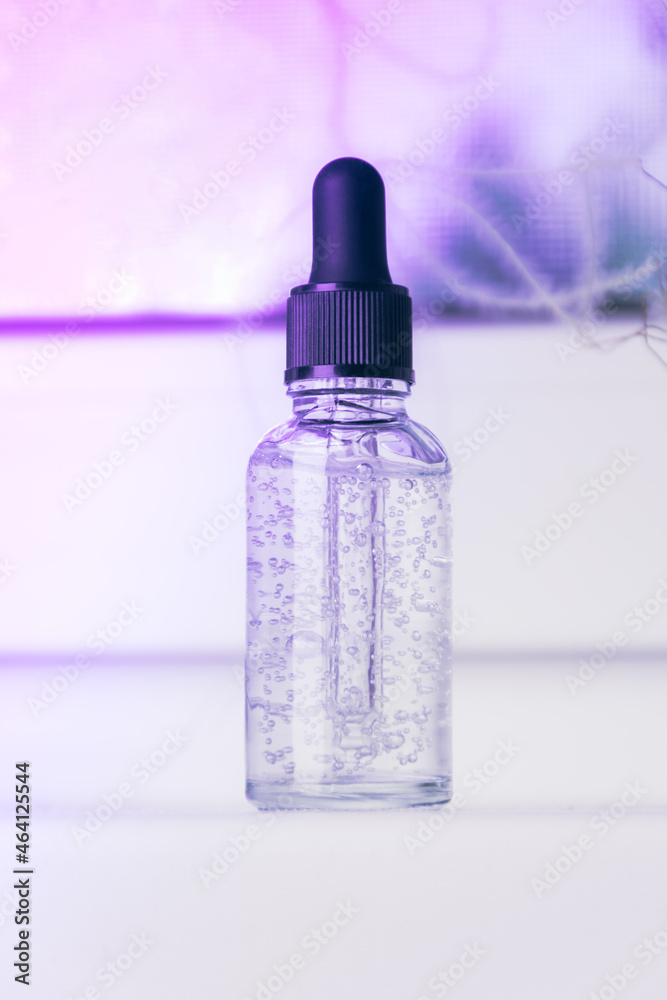 Glass bottle with liquid with bubbles on a neon background. Serum or essential aroma oil, aromatherapy and massage. Health and medicine concept, beauty and selfcare. Front view