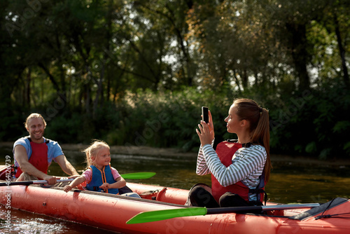 Girl taking picture of family on kayak on phone
