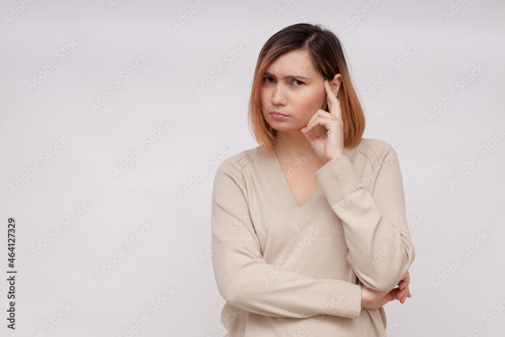 Human emotions, feelings, reaction and attitude. Attractive young woman squeezing eyes and keeping hand on temple in dissatisfaction and suspicion, feeling Human emotions, feelings, reaction and attitude. Attractive young woman squeezing eyes and keeping hand on temple in dissatisfaction and suspicion, feeling