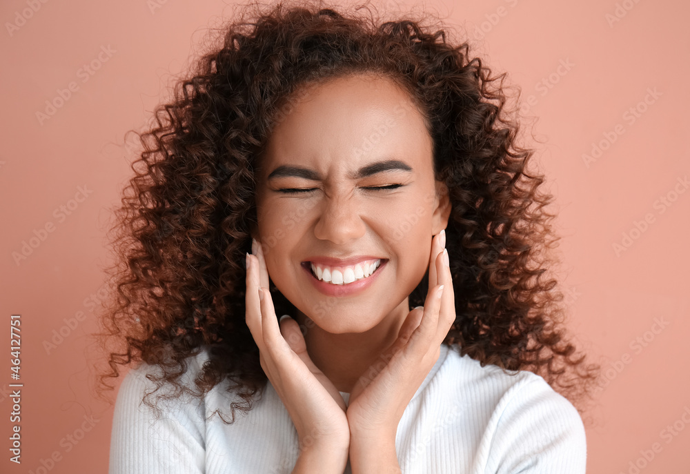 Young African-American woman with healthy hair on pink background Young African-American woman with healthy hair on pink background