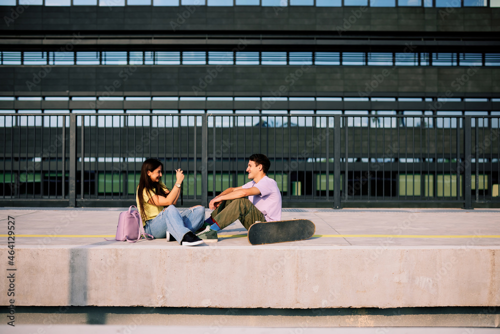 A happy teenage couple is sitting at the train station and taking photos. A happy teenage couple is sitting at the train station and taking photos.