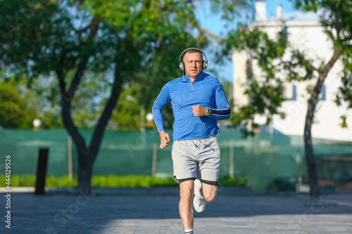Sporty mature man with headphones running in park