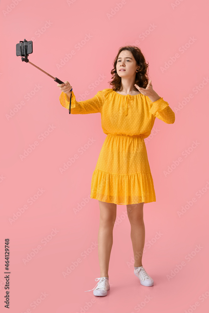 Pretty teenage girl taking video on pink background Pretty teenage girl taking video on pink background