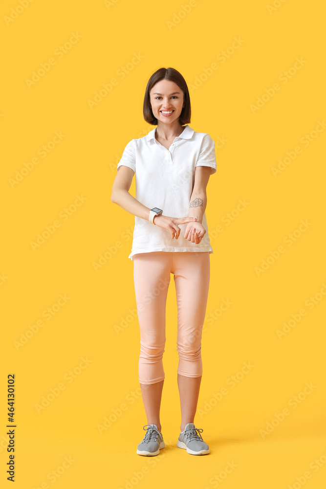 Obraz premium Sporty female runner checking pulse on color background