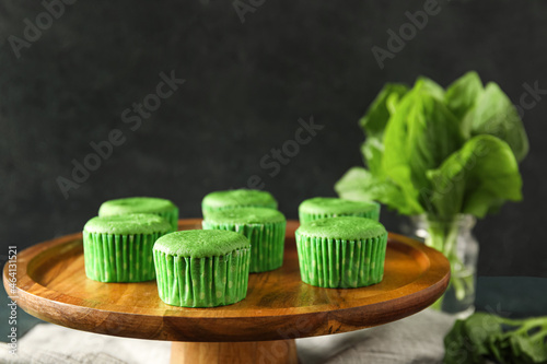 Wooden stand with tasty spinach muffins on dark background