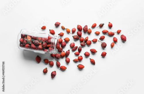 Jar with dried rose hip berries on white background