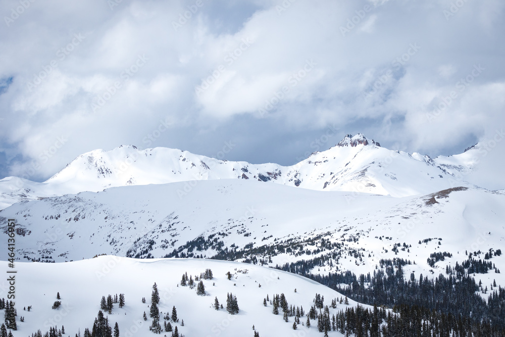 Snow covered mountain landscape with evergreen trees and dark clouds in Arapaho National Forest, Colorado