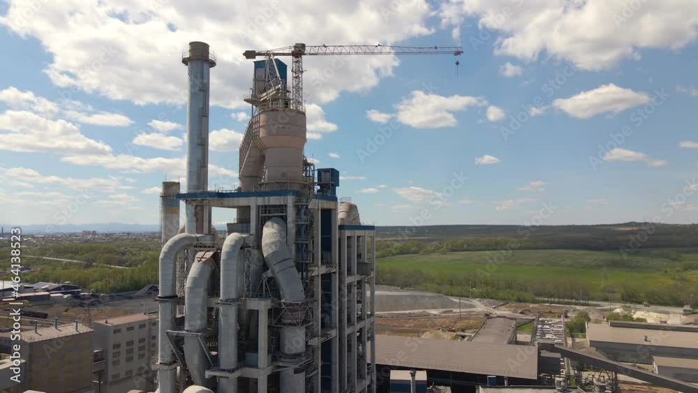Aerial view of cement factory with high concrete structure and tower crane at industrial production area. Manufacture and global industry concept. Aerial view of cement factory with high concrete structure and tower crane at industrial production area. Manufacture and global industry concept.