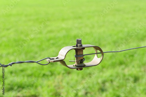 Soft focus of a fencing wire tensioner at a grassy field photo