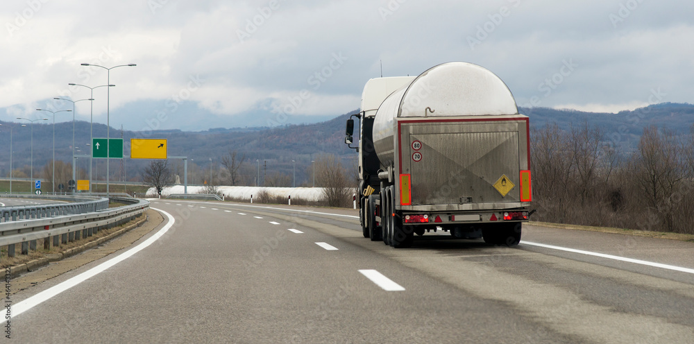 Isothermal Tank truck driving on highway. Oil and Gas Transportation and Logistics. Metal chrome cistern tanker with petrochemicals products. Liquid Chemical Freight.