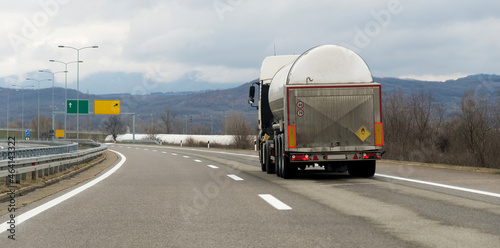 Isothermal Tank truck driving on highway. Oil and Gas Transportation and Logistics. Metal chrome cistern tanker with petrochemicals products. Liquid Chemical Freight.