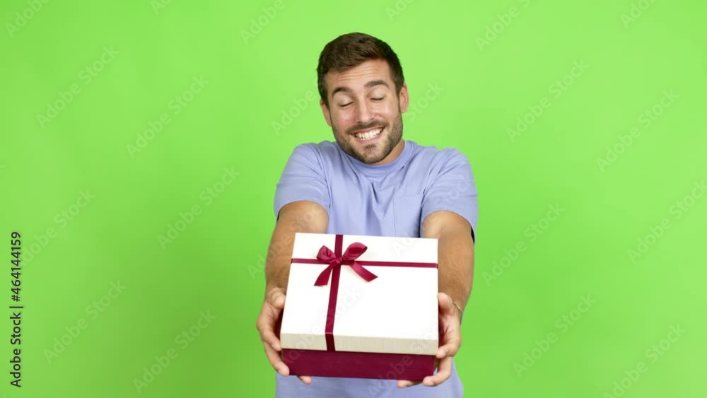 Handsome man happy and holding a gift over isolated background Handsome man happy and holding a gift over isolated background