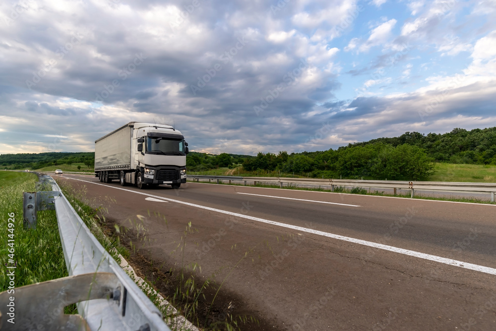 White truck coming from afar. Sunny summer day with blue skies and white clouds.