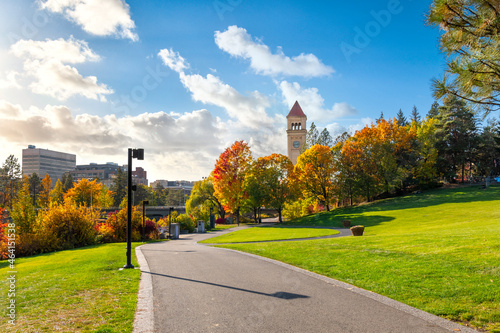 Walking trail and grassy area of Riverfront Park with the clock tower in view as leaves turn fall colors at late autumn in Spokane, Washington, USA photo