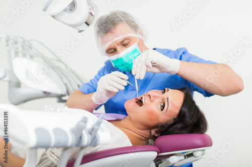 adult dentist checking teeth of patient woman sitting in medical center