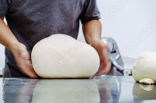Man preparing bread dough on table in a bakery factory.Dough ball for croissant bakery.pizza, bakery bread.Chef homemade bakery with hand.baker man make fresh dough prepare in kitchen.food pastry.