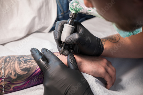 A tattoo artist works on a tattoo on the arm of a customer.