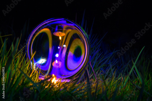 At night a glass ball in the grass on the street is lit by a candle, magic