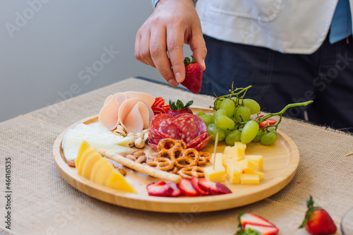 Unrecognizable man taking from a cold cuts and cheese platter