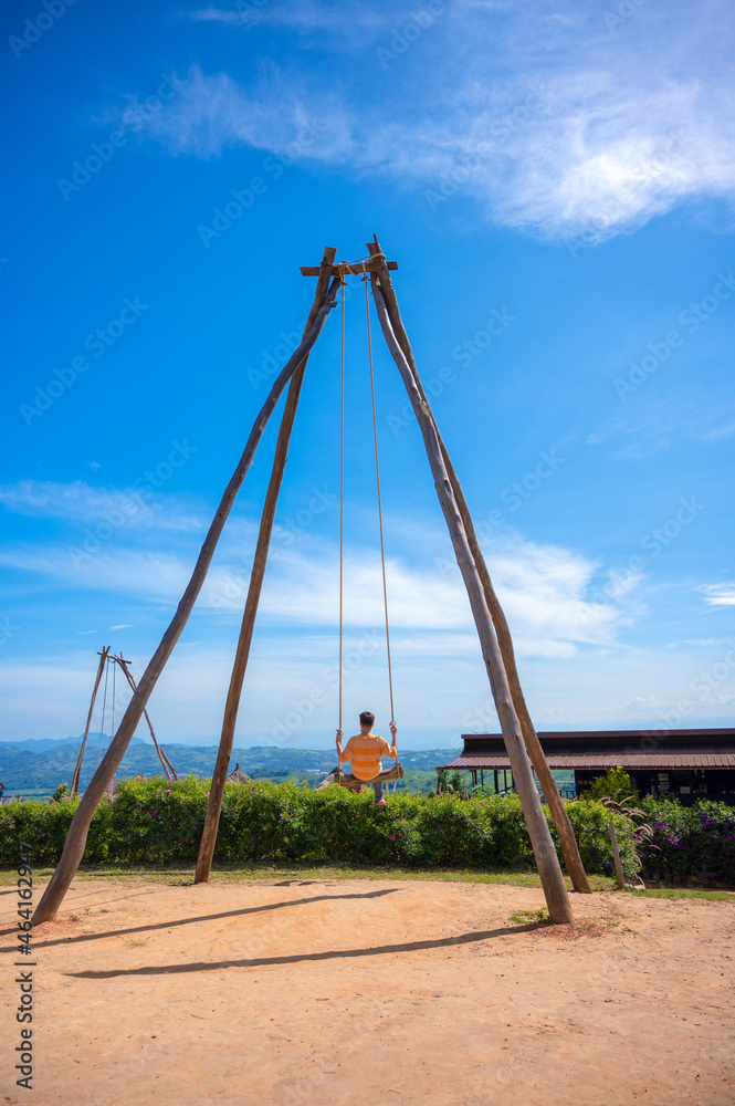 Male on swing in the mountains. Asian People relax on swing with the mountain view, Khao Kho, Phetchabun, Thailand. Male on swing in the mountains. Asian People relax on swing with the mountain view, Khao Kho, Phetchabun, Thailand.