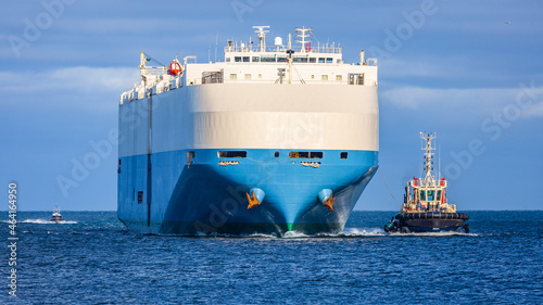 Cargo Ship steaming into port being escorted by a tug.
