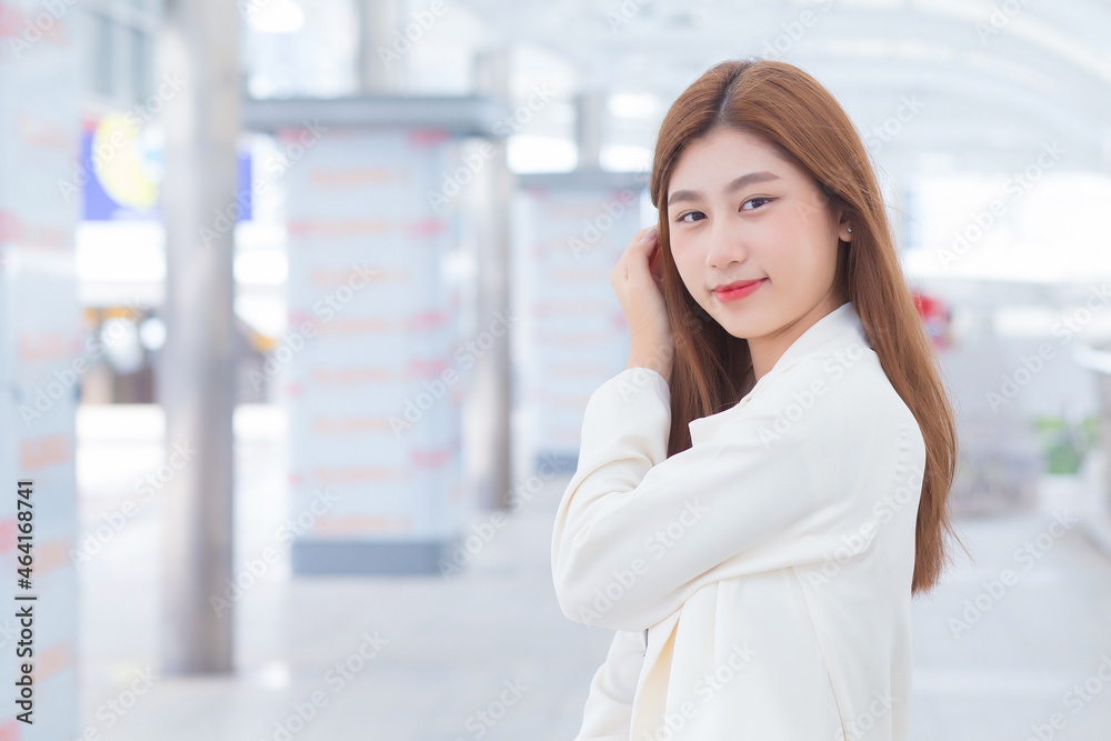 Young Asian working woman looking at camera in white is out to meet a client at the office in a happy mood. Young Asian working woman looking at camera in white is out to meet a client at the office in a happy mood.