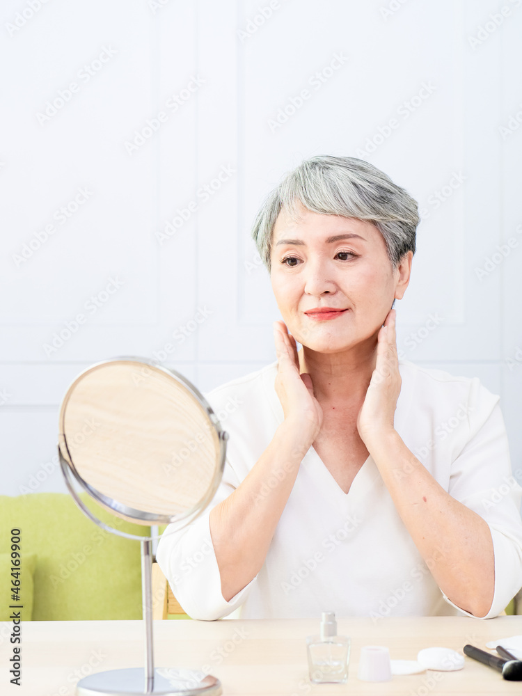 Senior Asia woman is spraying perfume at home. Senior Asia woman is spraying perfume at home.
