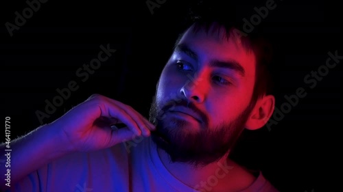 Portrait handsome man combing beard colorful neon led light. Fashion hipster prepare shave ultraviolet illuminance. Led lighting unshaven guy. Bearded people shaving neon illumination in ultra violet.