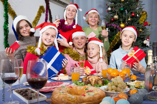Positive family sitting with gifts at celebrating New Year at dinner