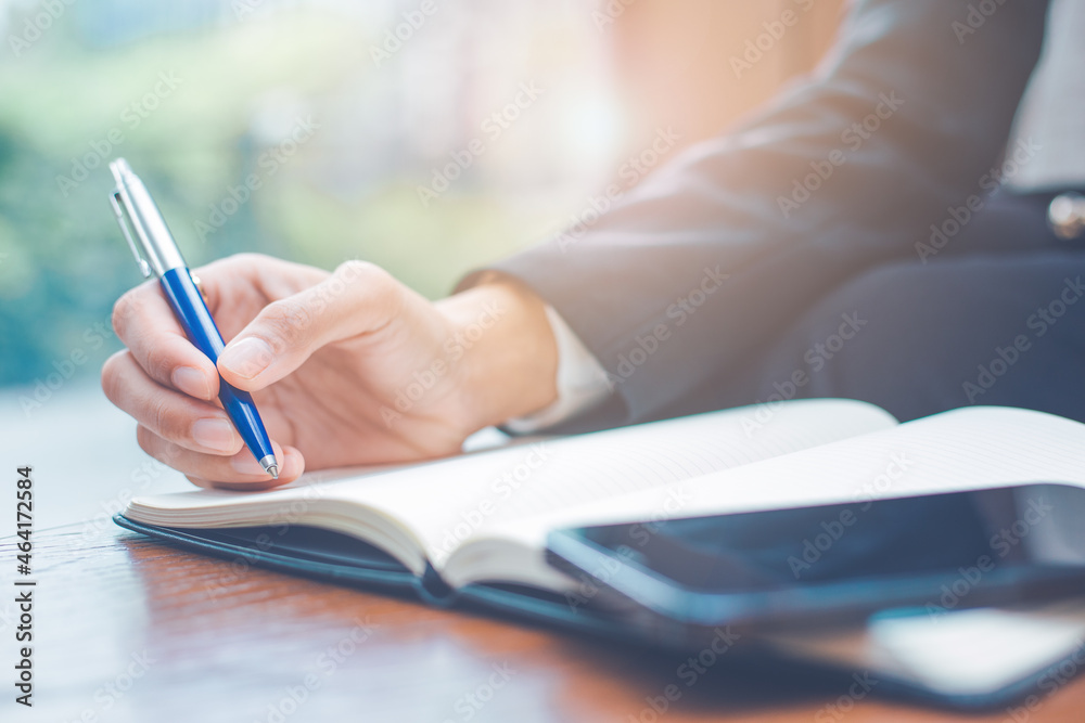 Business woman hand writing on a notepad with a pen in the office.