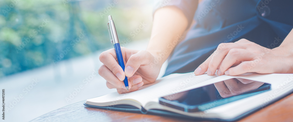 Business woman hand writing on a notepad with a pen in the office.