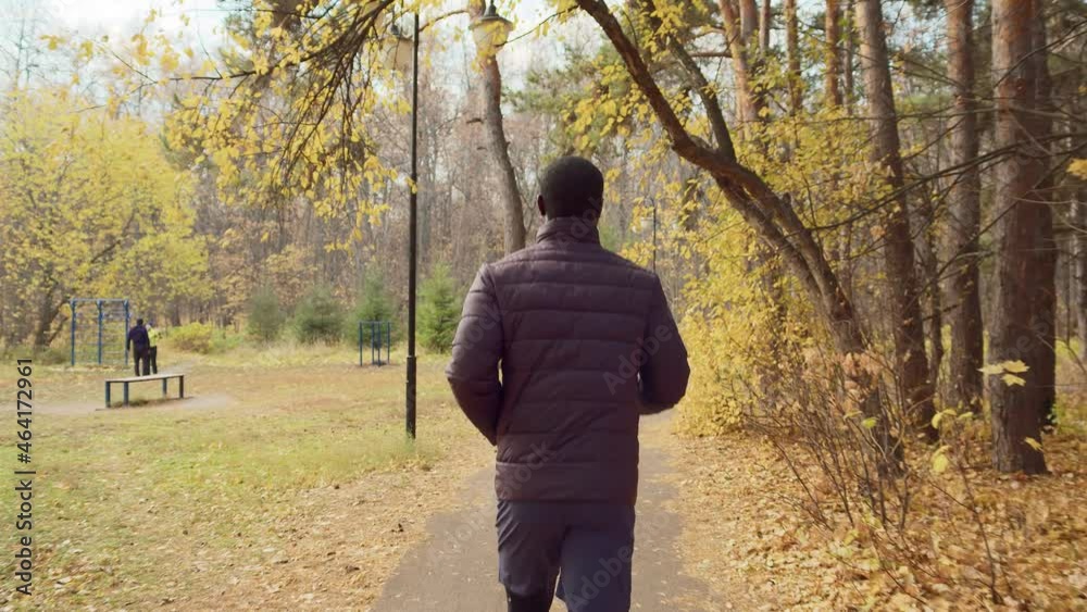 Jogging in the old park in the autumn morning. The young man moves towards the workout area. Easy warm-up before training. Outdoor sports. High quality. 4k footage. Jogging in the old park in the autumn morning. The young man moves towards the workout area. Easy warm-up before training. Outdoor sports. High quality. 4k footage.