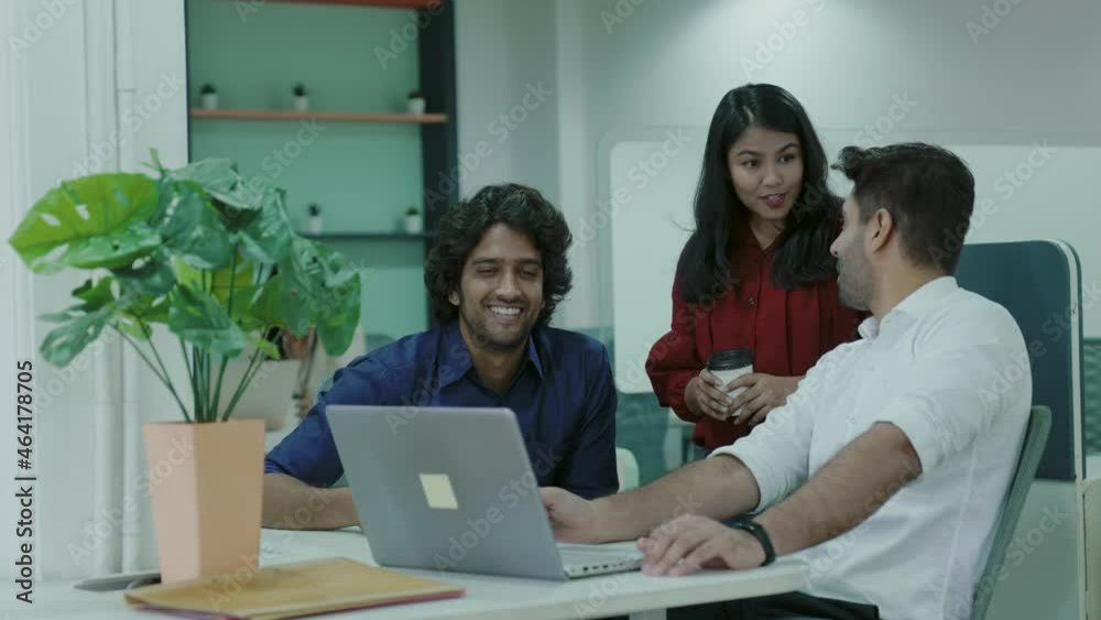 Diverse young indian people colleagues talk looking at laptop discuss teamwork.corporate Asian business people looking at a laptop having conversation.