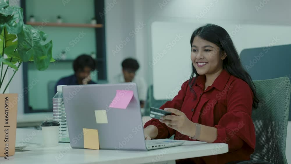 Young Indian woman using laptop at office and holding credit card, buying food clothes or, international online shopping,work from home concept. guy typing on laptop keyboard, paying credit card. Young Indian woman using laptop at office and holding credit card, buying food clothes or, international online shopping,work from home concept. guy typing on laptop keyboard, paying credit card.