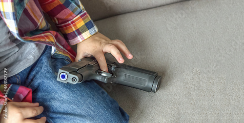 Child plays with a pistol, firearms. Gun in children's hands