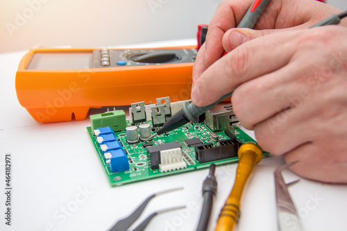 Male measures voltage with an ammeter on a printed circuit board. Electronics repair with tester. Selective focus. © Александра Замулина