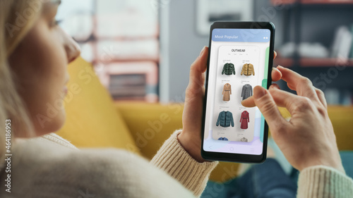Obraz na plátne Beautiful Caucasian Female is Using Smartphone with Clothing Online Web Store to Choose and Buy Clothes from New Collection