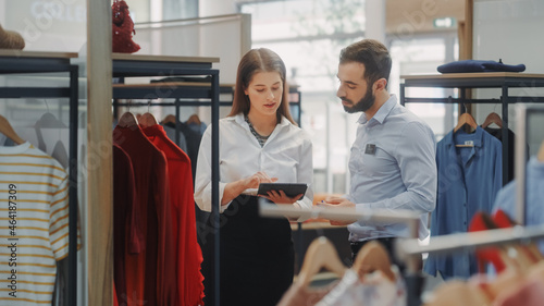 Clothing Store: Businesswoman Uses Tablet Computer, Talks to Visual Merchandising Specialist, Collaborate To Create Stylish Collection. Small Business Fashion Shop Sales Manager Talks to Designer