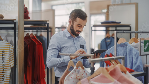 Φωτογραφία Clothing Store: Male Visual Merchandising Professional Uses Tablet Computer To Create Collection