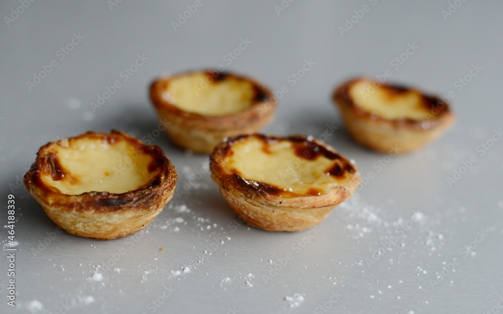 Egg tart, traditional Portuguese dessert, pastel de nata, pasteis on a plate. Grey stone background.