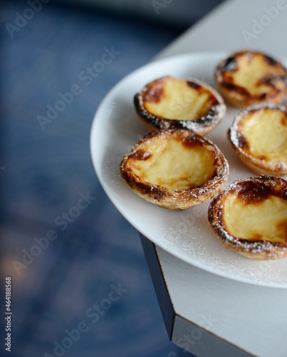 Egg tart, traditional Portuguese dessert, pastel de nata, pasteis on a plate. Grey stone background.