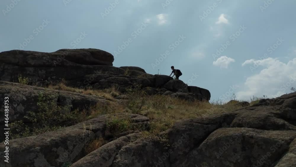 Silhouette of a teenager hiking in the mountains with a backpack on a summer day