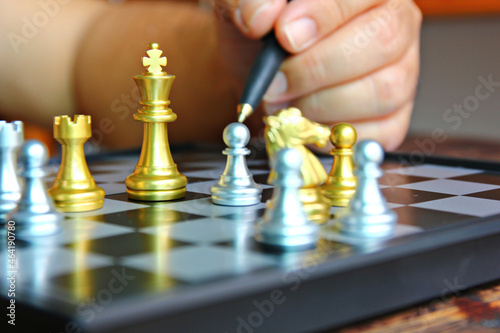 golden king chess among chess pieces on board with blur hand holding black pen