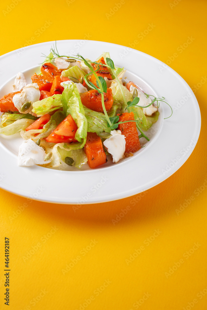 Fresh Greek salad with tomato, cucumber, bell pepper, Peking cabbage, feta cheese and vegetable sauce. Healthy food, vegetarian dieting, close up on yellow isolated background Fresh Greek salad with tomato, cucumber, bell pepper, Peking cabbage, feta cheese and vegetable sauce. Healthy food, vegetarian dieting, close up on yellow isolated background