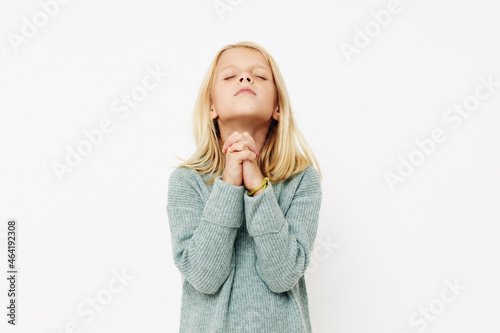 Beautiful little girl gestures with his hands on a light background