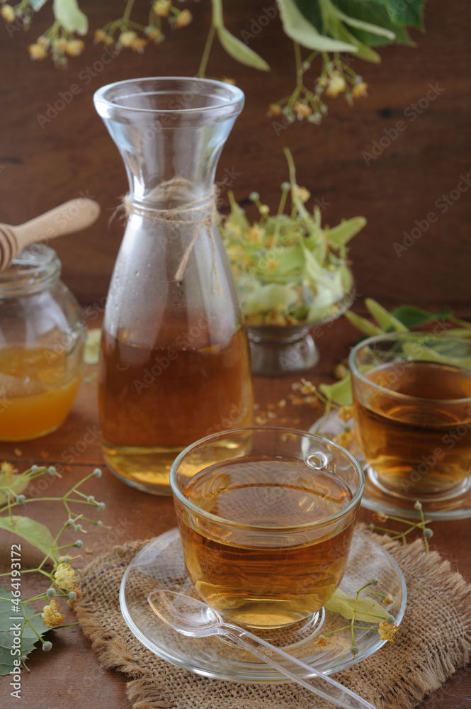 Hot herbal tea with linden flowers and honey on wooden background in sunshine Hot herbal tea with linden flowers and honey on wooden background in sunshine