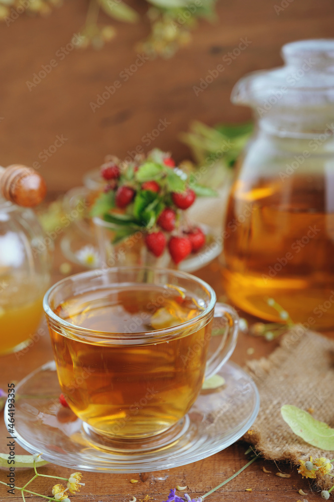 Teapot and cups of herbal tea with herbal flowers and strawberries on wooden table Teapot and cups of herbal tea with herbal flowers and strawberries on wooden table