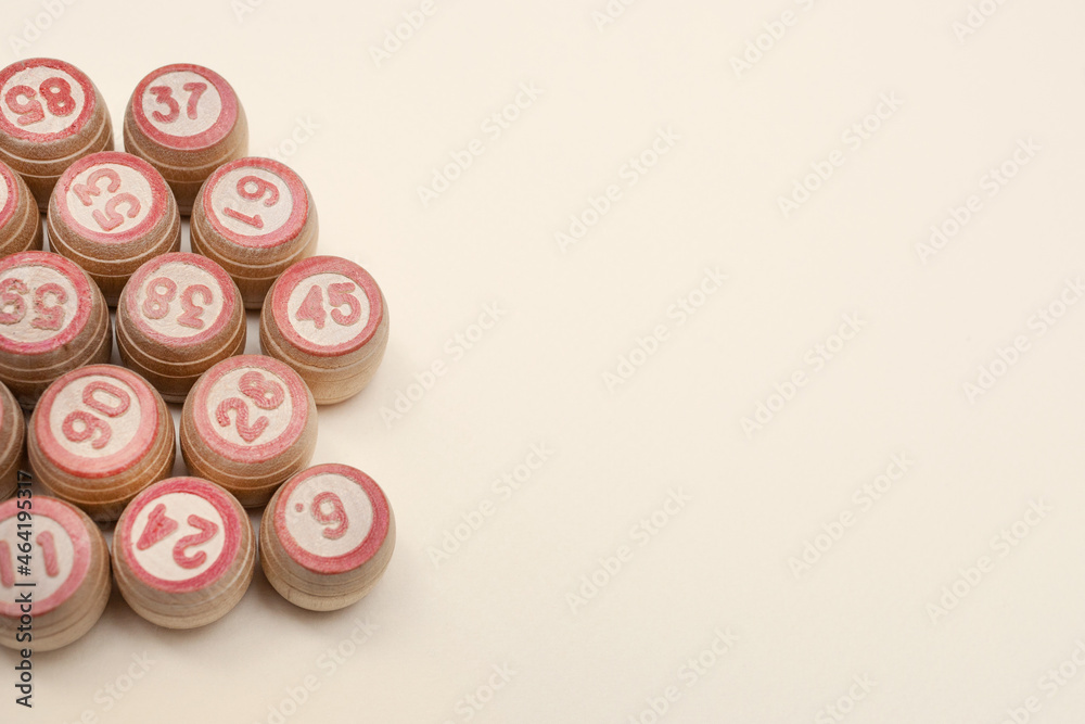 Wooden barrels with numbers for playing lotto or bingo. Beige background. Place for your text. Copy space. Advertising. Flat lay. Leisure with family. Wooden barrels with numbers for playing lotto or bingo. Beige background. Place for your text. Copy space. Advertising. Flat lay. Leisure with family.