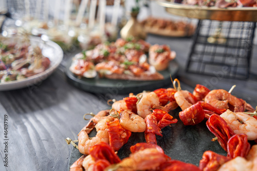 Delicious fresh seafood, shrimp with fresh vegetables. buffet table with lots of delicious snacks. canapes, bruschetta, and little desserts on wooden plate board